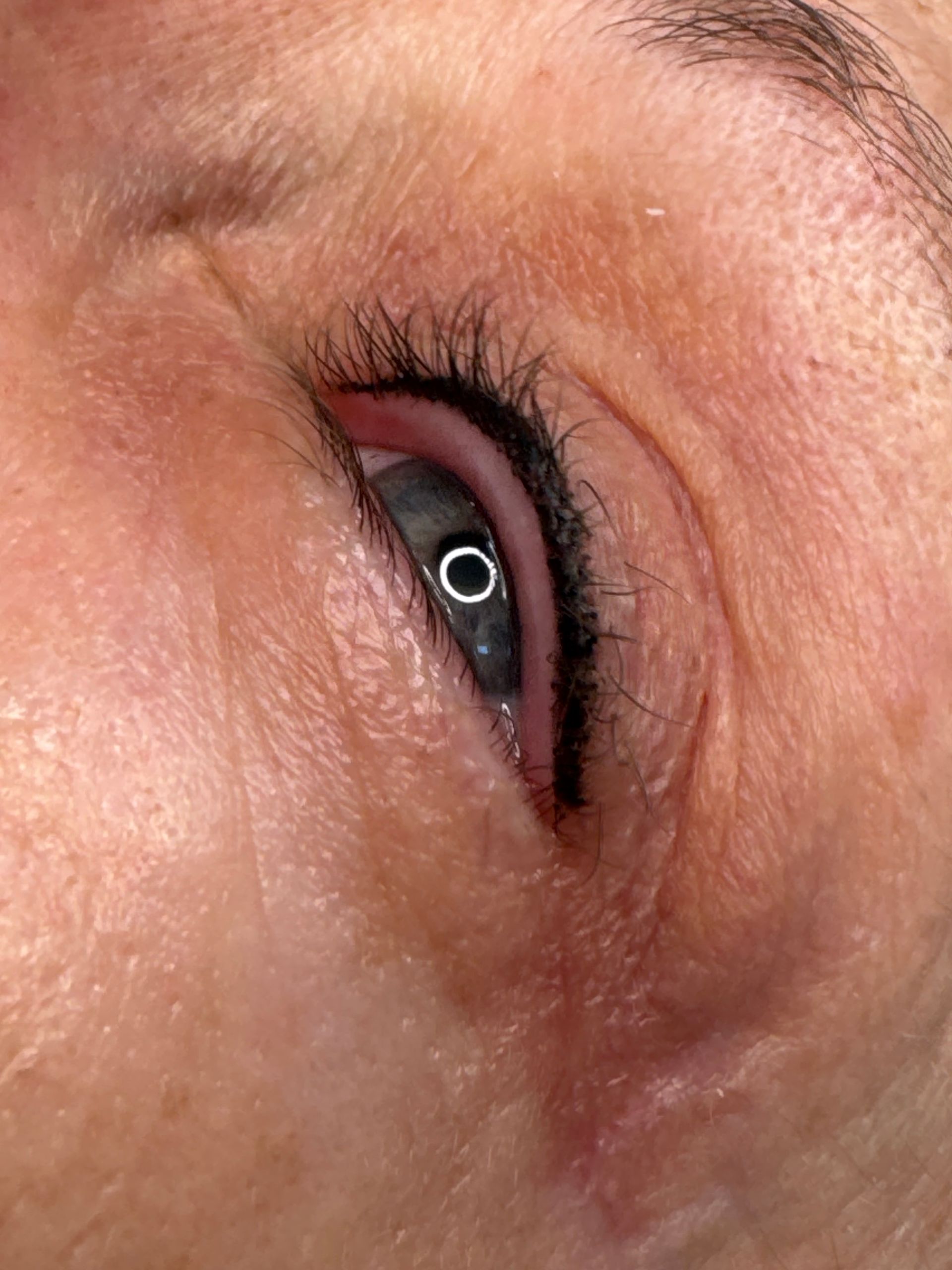 Close-up of a closed eye with a white ring-shaped contact lens or reflection visible on the iris