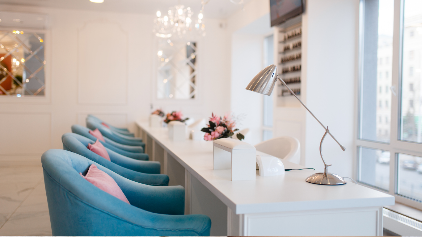 Modern white salon with turquoise chairs and a long counter by large windows