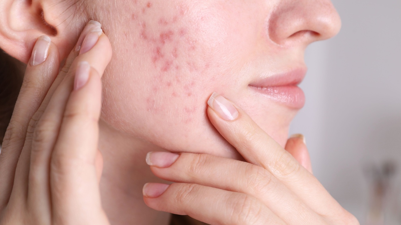 Close-up of a person gently touching their cheek and jawline in a soft-lit skincare scene