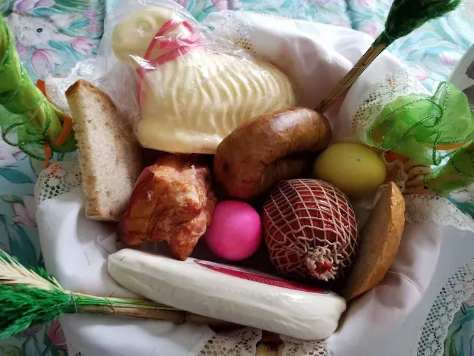 Easter basket with traditional foods: bread, sausage, ham, eggs, and a lamb-shaped butter.