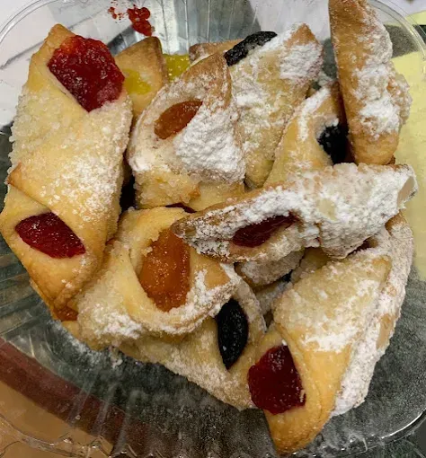Close-up of pastries with fruit fillings, dusted with powdered sugar, in a glass bowl.