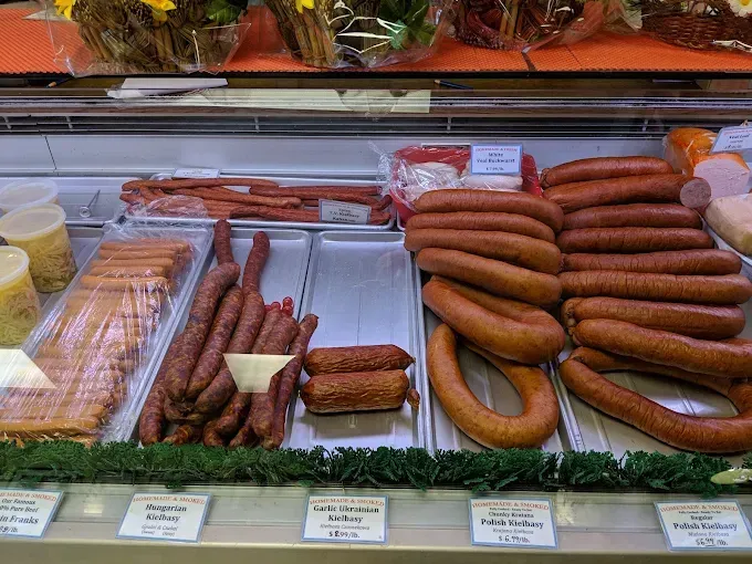 Display case with various sausages and meats at a deli.