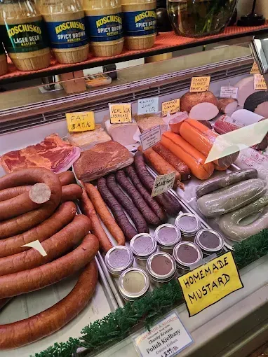 A deli case filled with various sausages, meats, and homemade mustards.