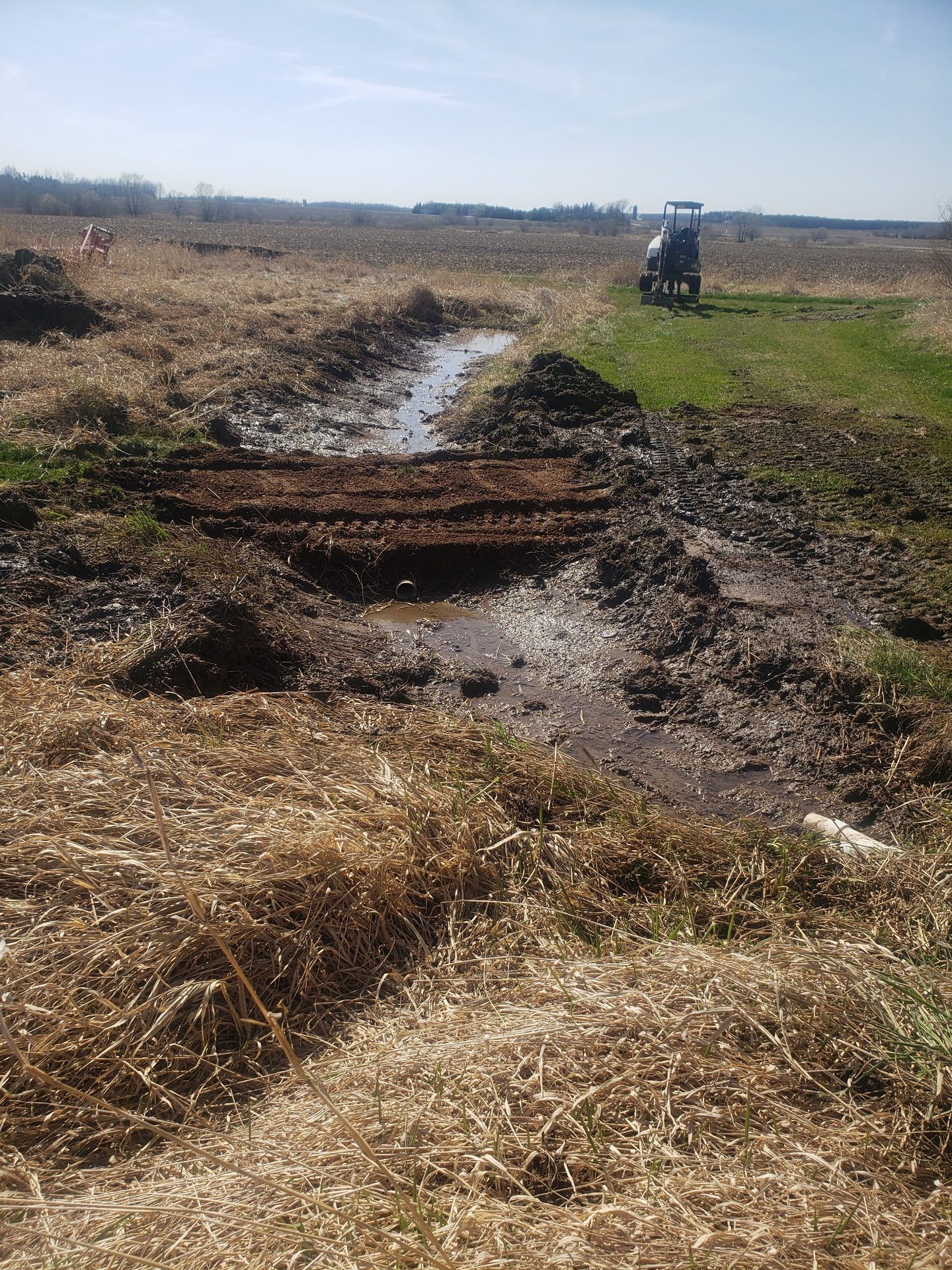 Newly installed field culvert crossing with water flowing through the reshaped ditch in Dorchester, WI