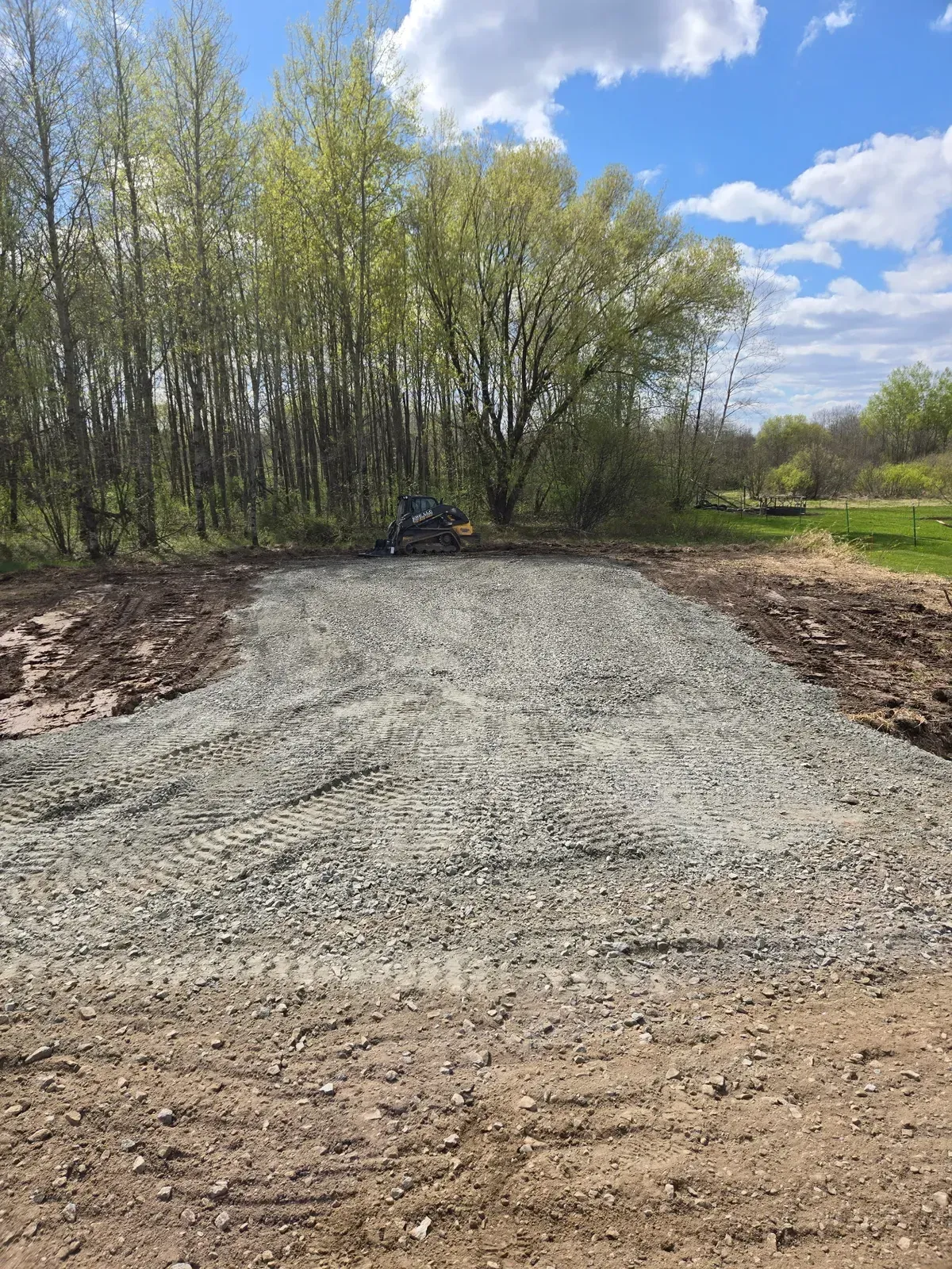 Finished gravel parking pad and driveway with an ERE skid steer at the edge in Curtiss, WI – ERE Excavation