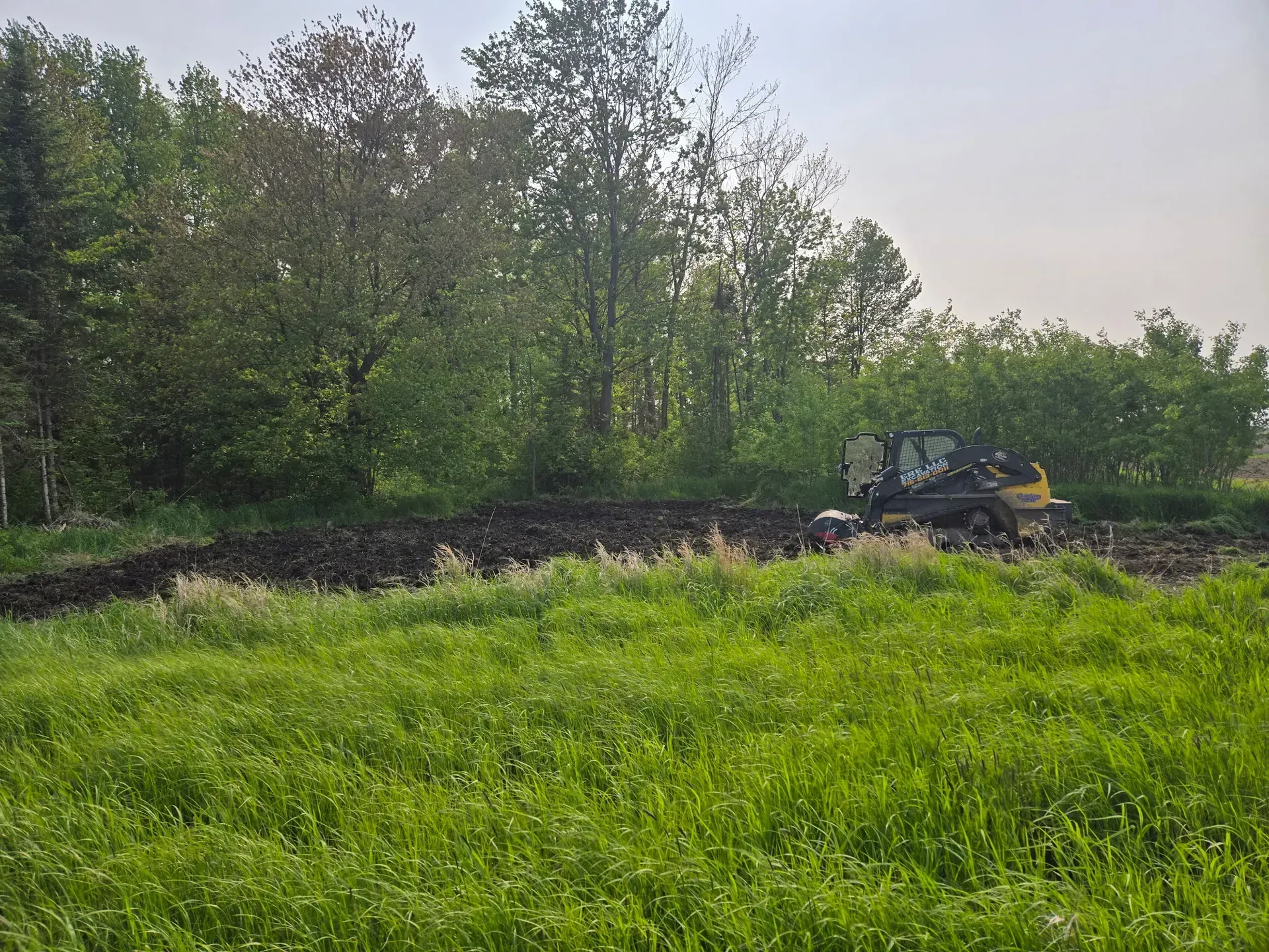 ERE Excavation compact track loader tilling a food plot along a wooded edge in Abbotsford, WI