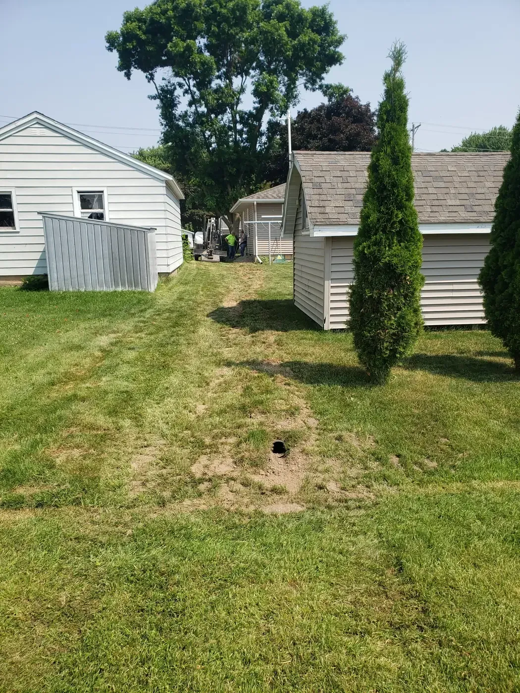French drain discharge outlet at the end of a restored trench between two outbuildings in Marshfield, WI