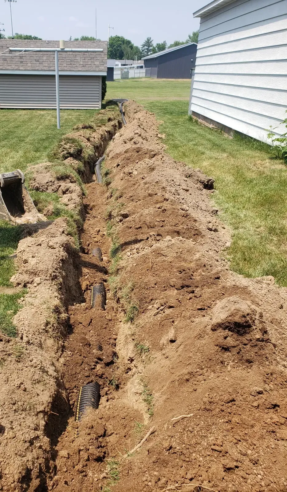 Corrugated discharge pipe laid in a long backyard trench to carry water away from the house in Marshfield, WI