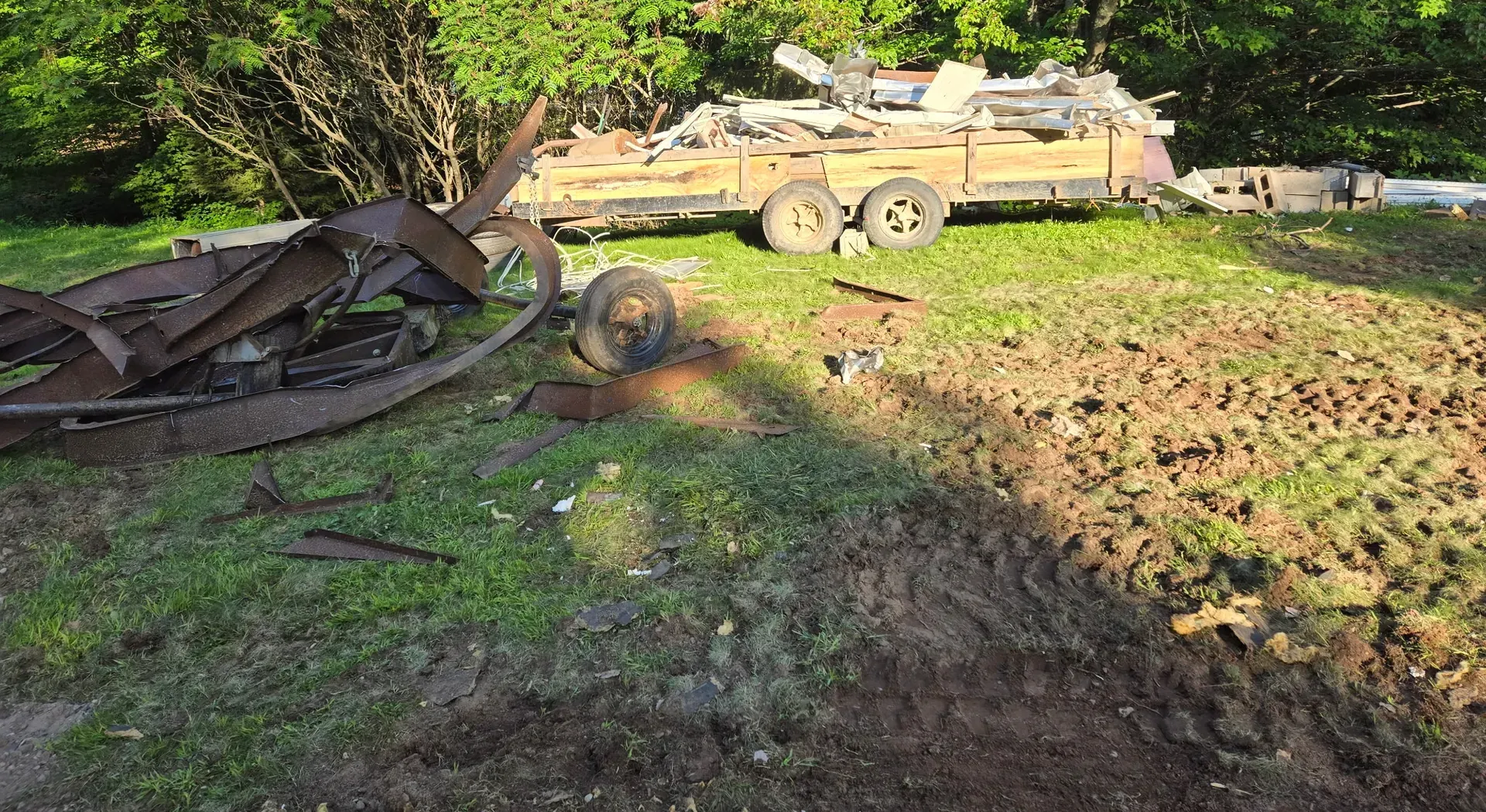 Twisted steel mobile home chassis and a trailer loaded with metal siding and roofing hauled off after demolition in Phillips, WI