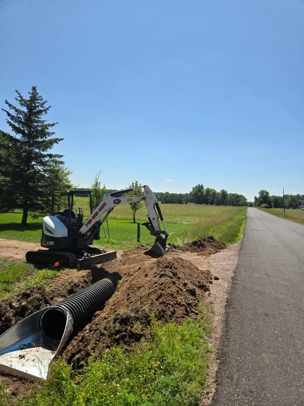 New corrugated culvert pipe set in a roadside trench with galvanized end section in Marshfield, WI
