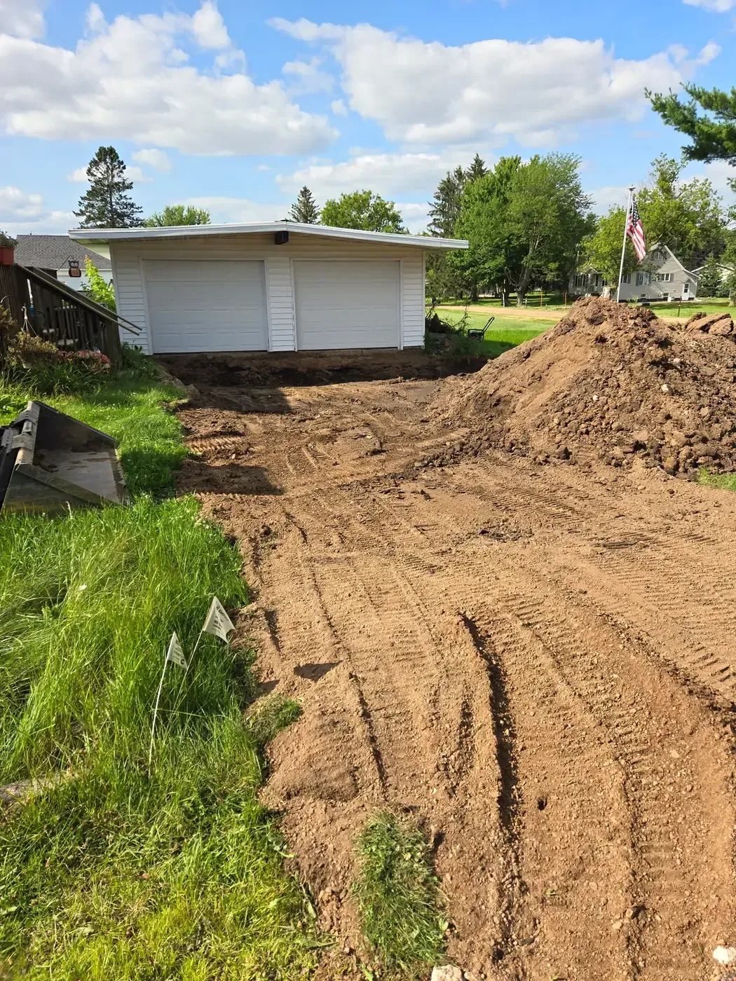 Residential driveway excavated down to subgrade with utility locate flags marked in Colby, WI