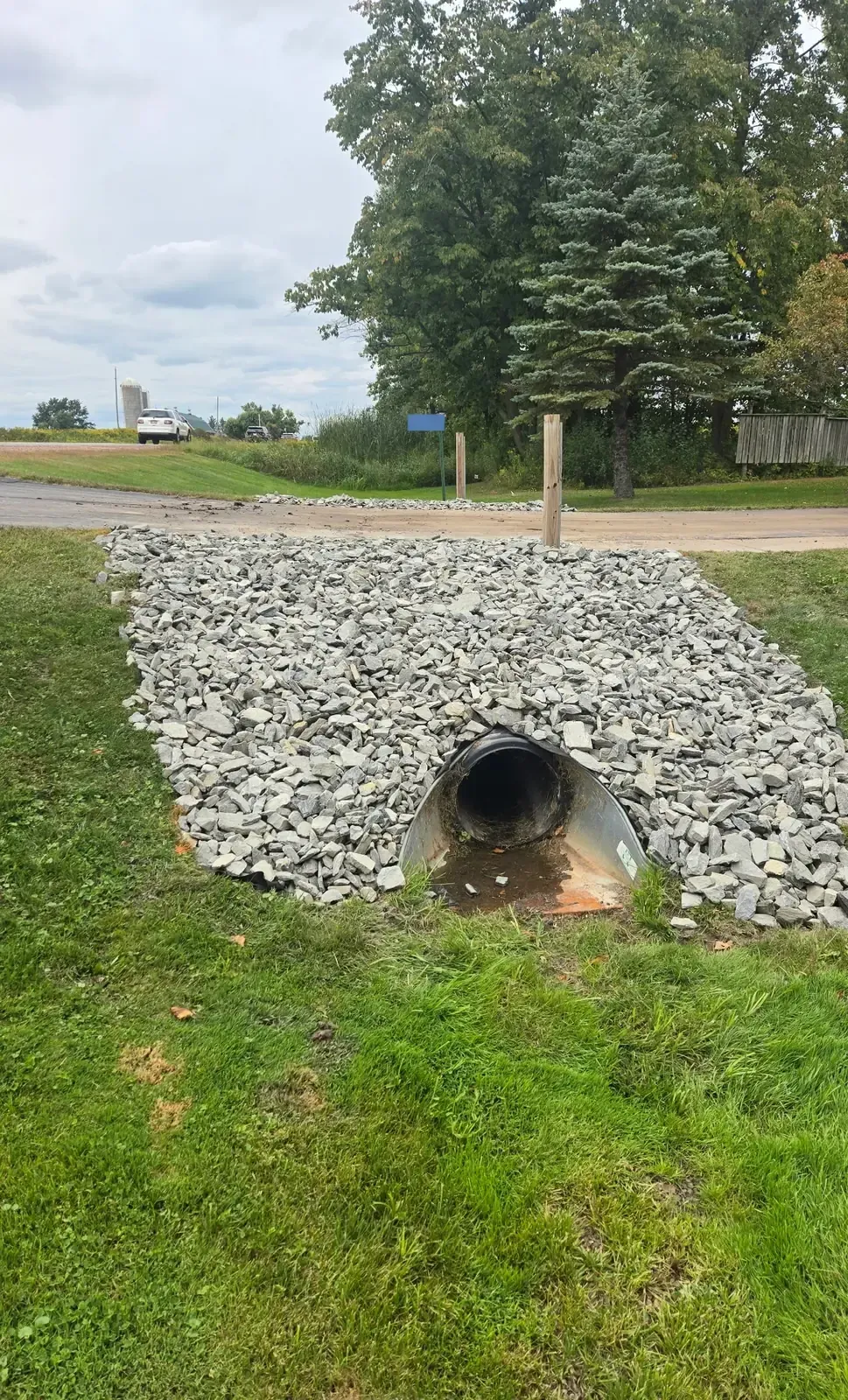 Driveway culvert outlet with galvanized flared end section armored with riprap stone in Marshfield, WI