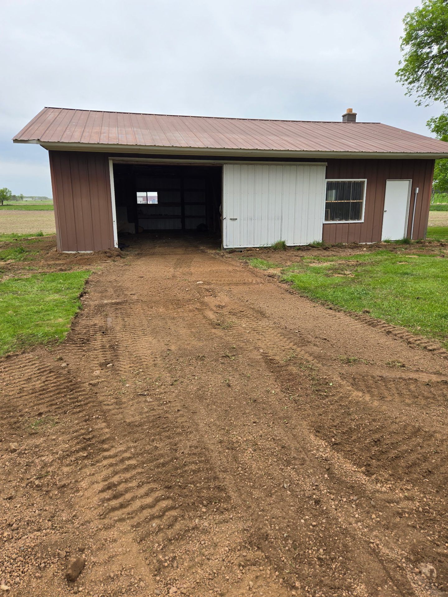Graded dirt apron prepped for gravel in front of a pole shed’s sliding door in Dorchester, WI
