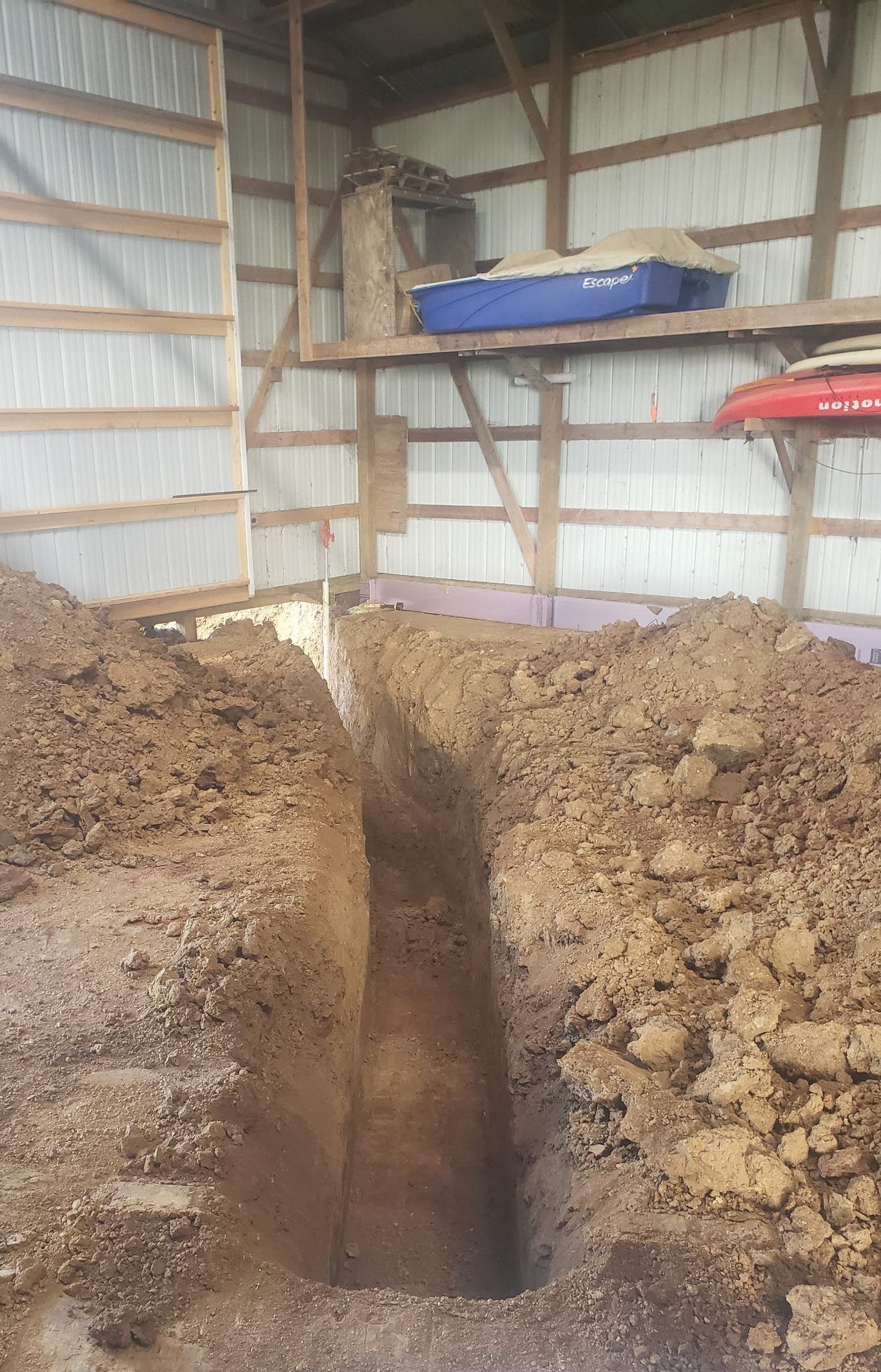 Deep, clean-cut trench for a new water line running across a pole shed floor to the wall in Dorchester, WI