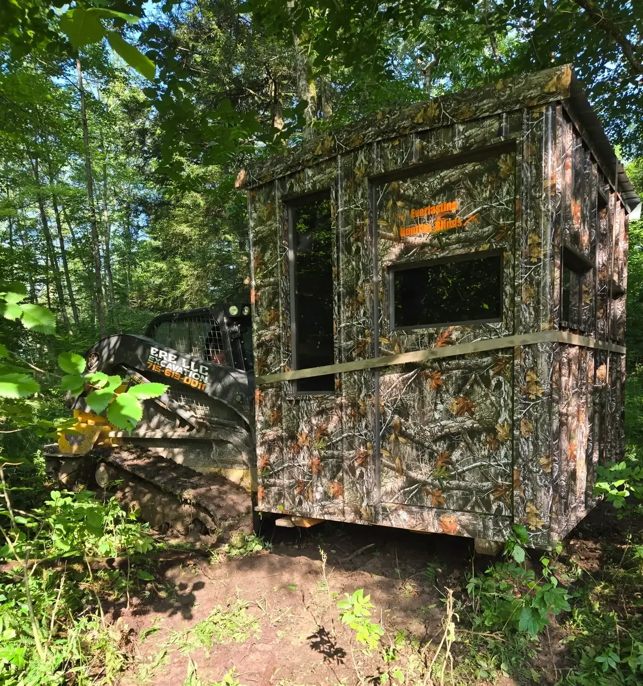 ERE Excavation track loader setting a hunting blind on a prepared site in the woods near Colby, WI