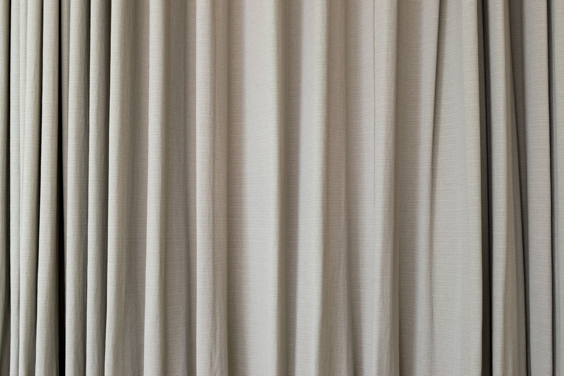 Tende plissettate beige, chiuse, riempiono l'intera stanza.