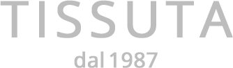 Logo grigio “TISSUTA” con la scritta “dal 1987” sotto, su sfondo bianco.