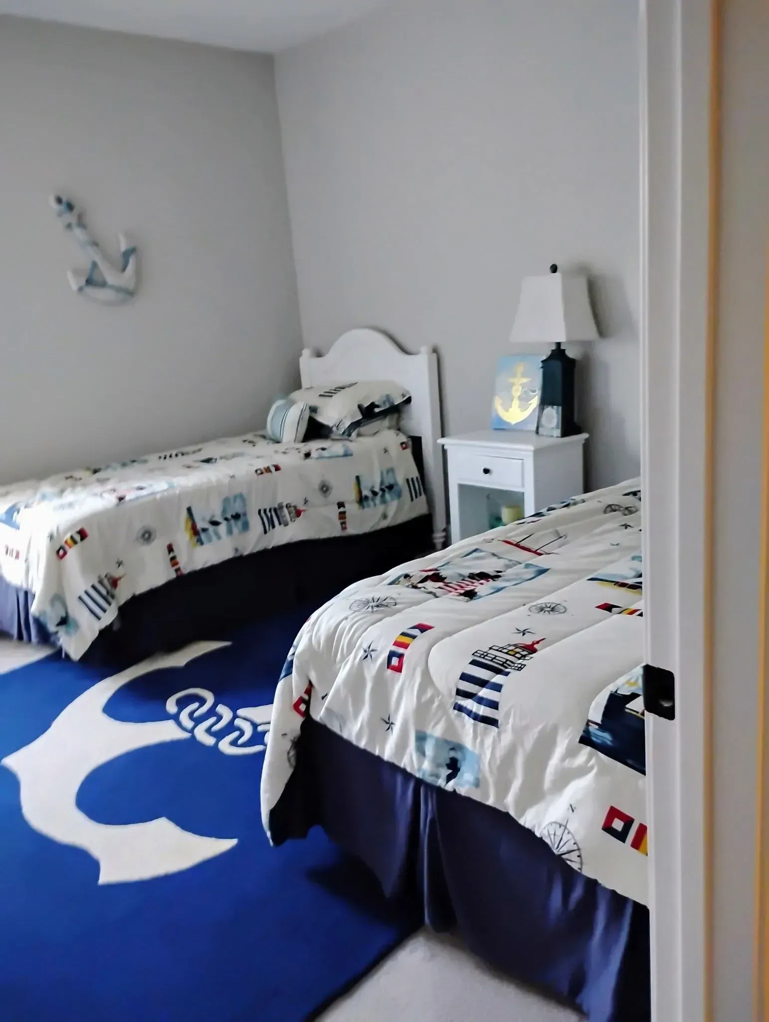 Bedroom with two twin beds, nautical theme, blue and white colors, anchor rug.