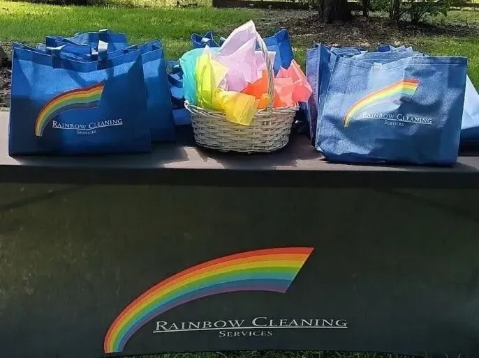 Blue tote bags and a basket with rainbow tissue paper and a rainbow logo that reads, 