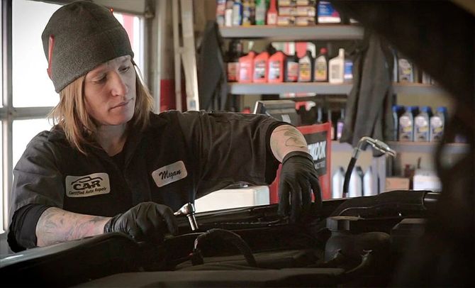 A woman is working on a car in a garage. | Certified Auto Repair