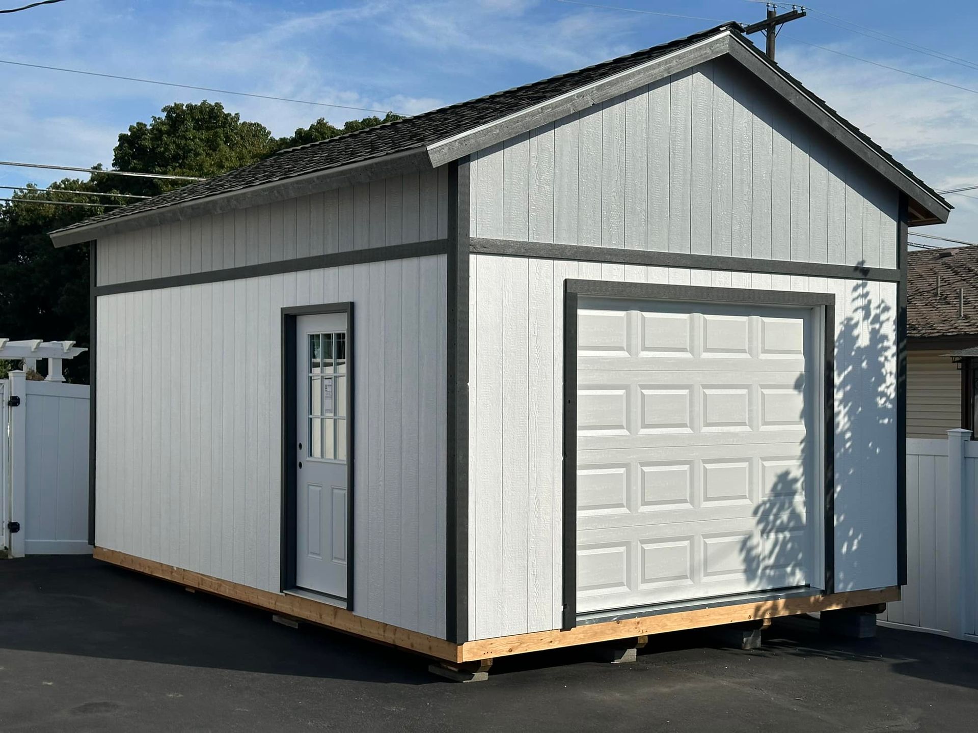 A small white garage with a garage door and a window.