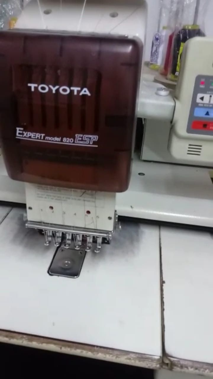 Un cabezal de máquina de bordar Toyota Expert con las agujas colocadas sobre una mesa de costura.