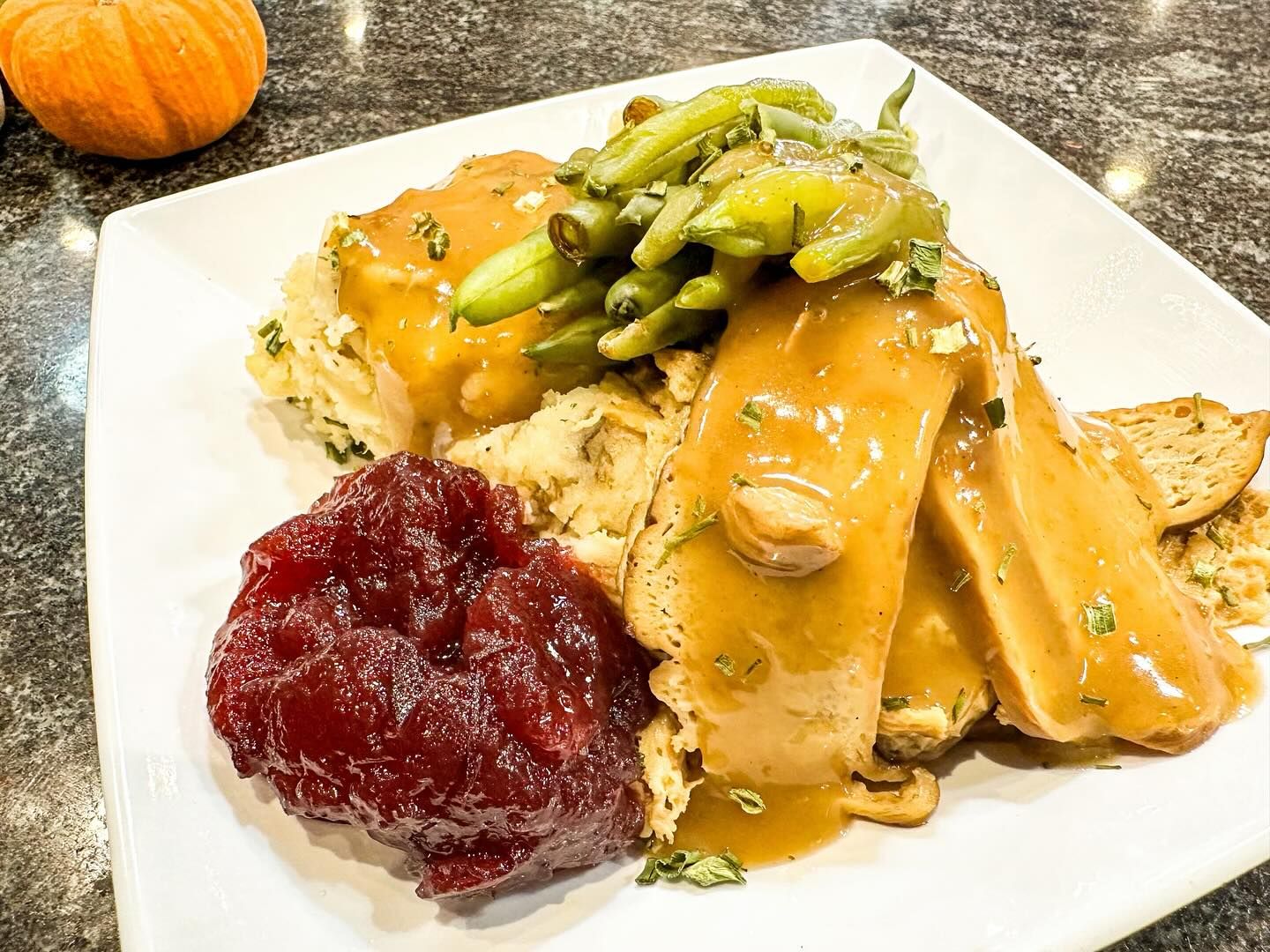 Thanksgiving plate with turkey, cranberry sauce, green beans, mashed potatoes, and gravy.