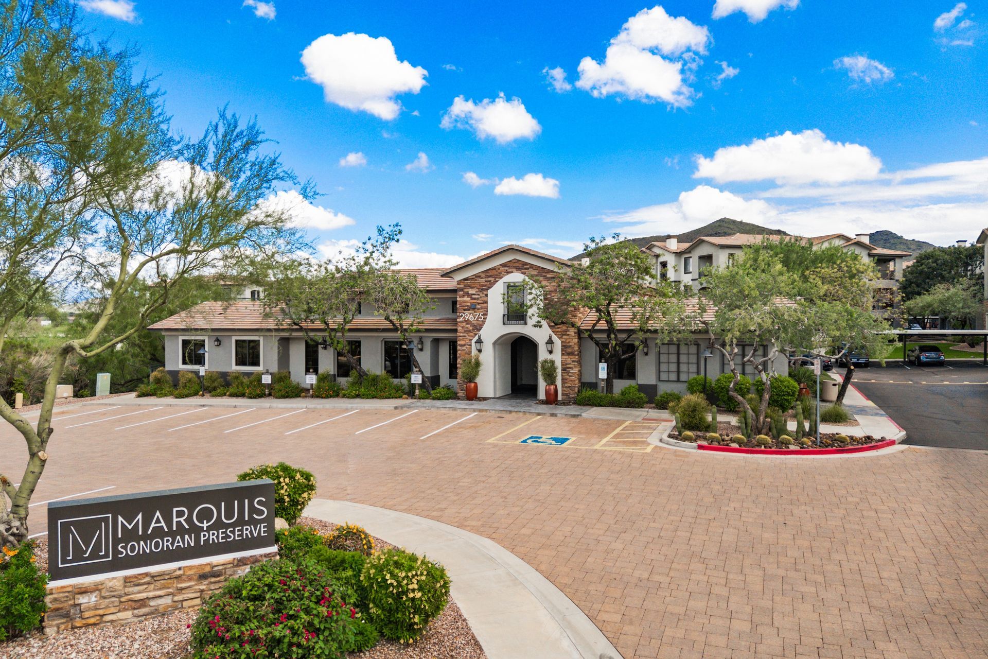 Marquis at Creekside apartment entrance with landscaped driveway and blue sky