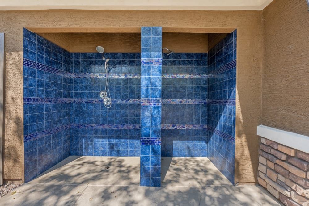Blue-tiled outdoor shower stall with a central divider and brick wall accents
