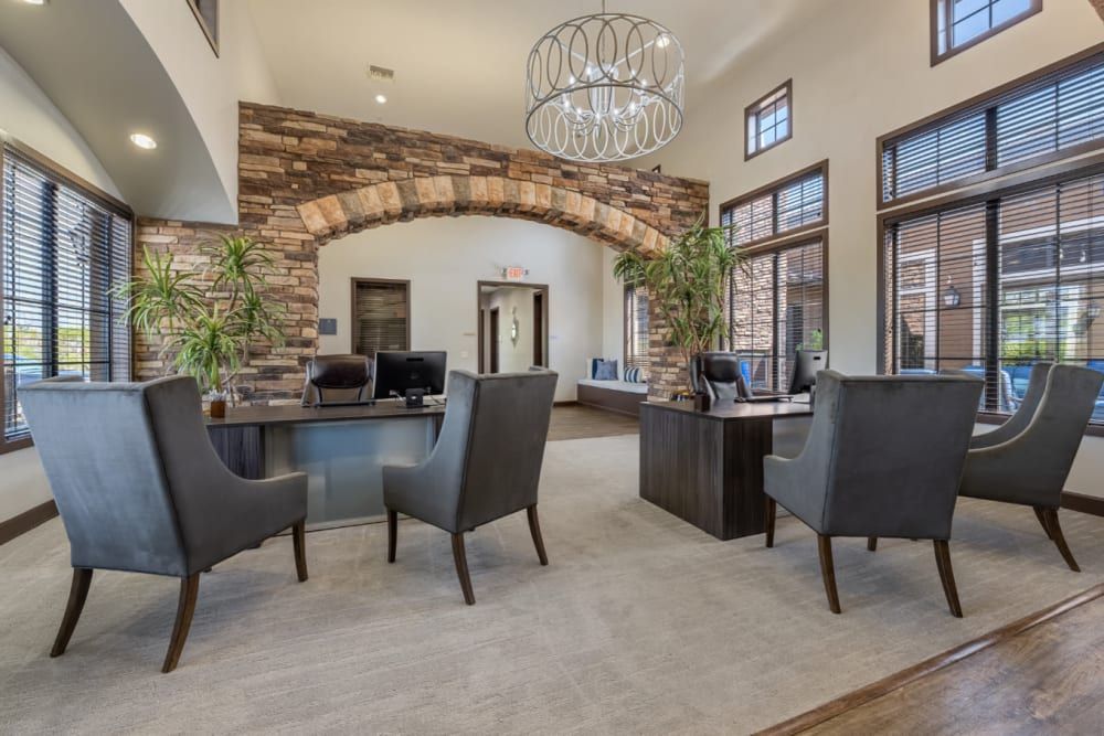 Clubhouse lobby with stone arch, glass table, dark chairs, and large windows