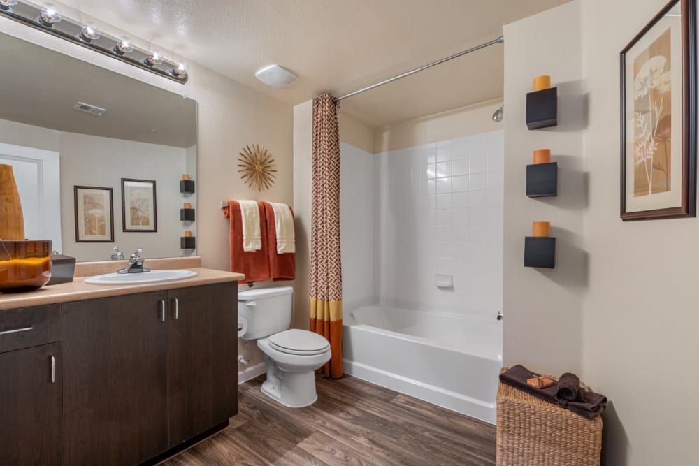 Modern bathroom with dark wood vanity, white tub, patterned shower curtain, and wall art