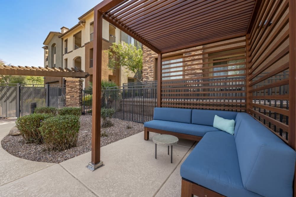 Apartment outdoor lounge with a couch and a table under a pergola at Marquis Sonoran Preserve in Norterra Phoenix, AZ.