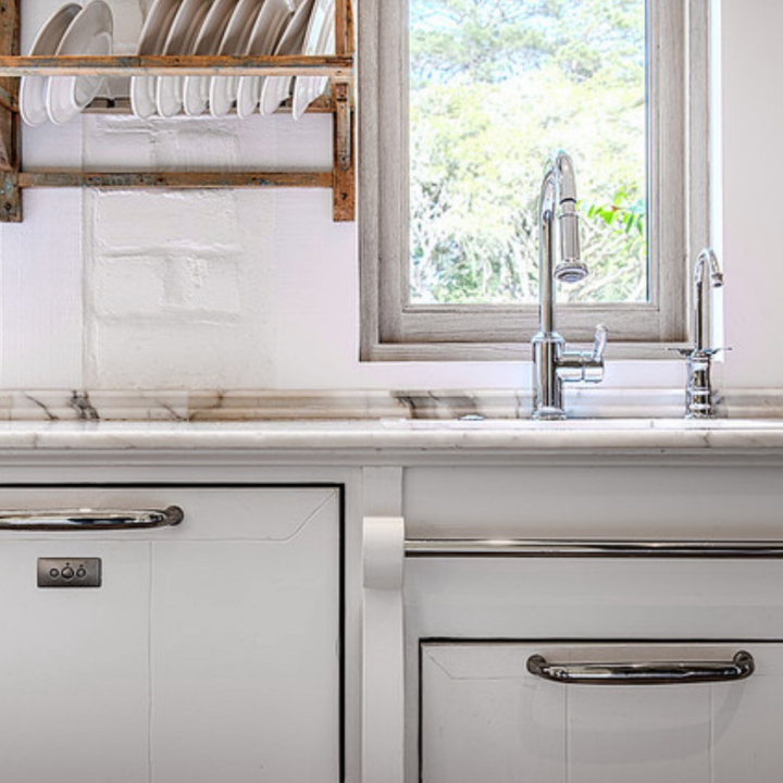 White kitchen with dishes drying rack, window, and stainless steel faucet.