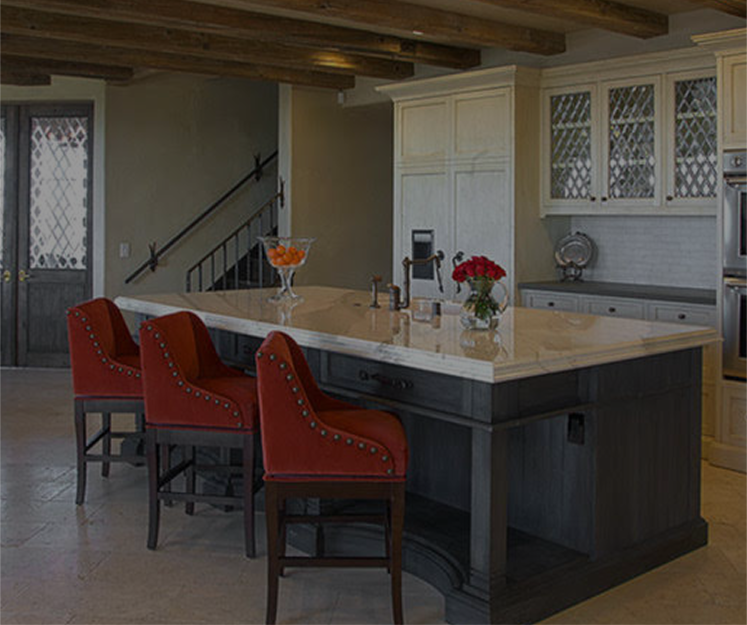 Kitchen with island, red stools, wood beams, and white cabinets.