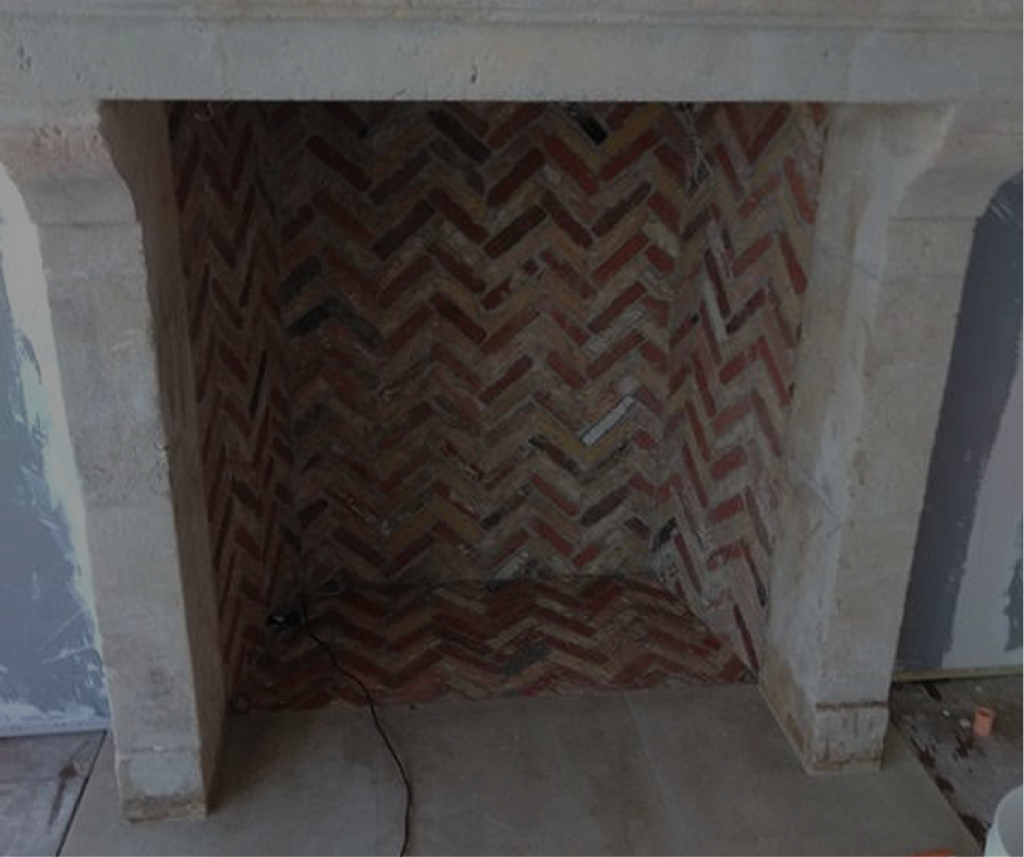 Fireplace with red brick herringbone pattern inside the opening, framed by a stone mantel.