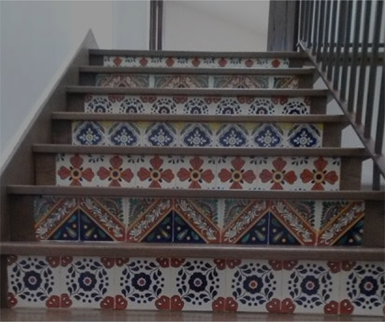 Staircase with decorative, patterned tile risers in shades of blue, red, and yellow.
