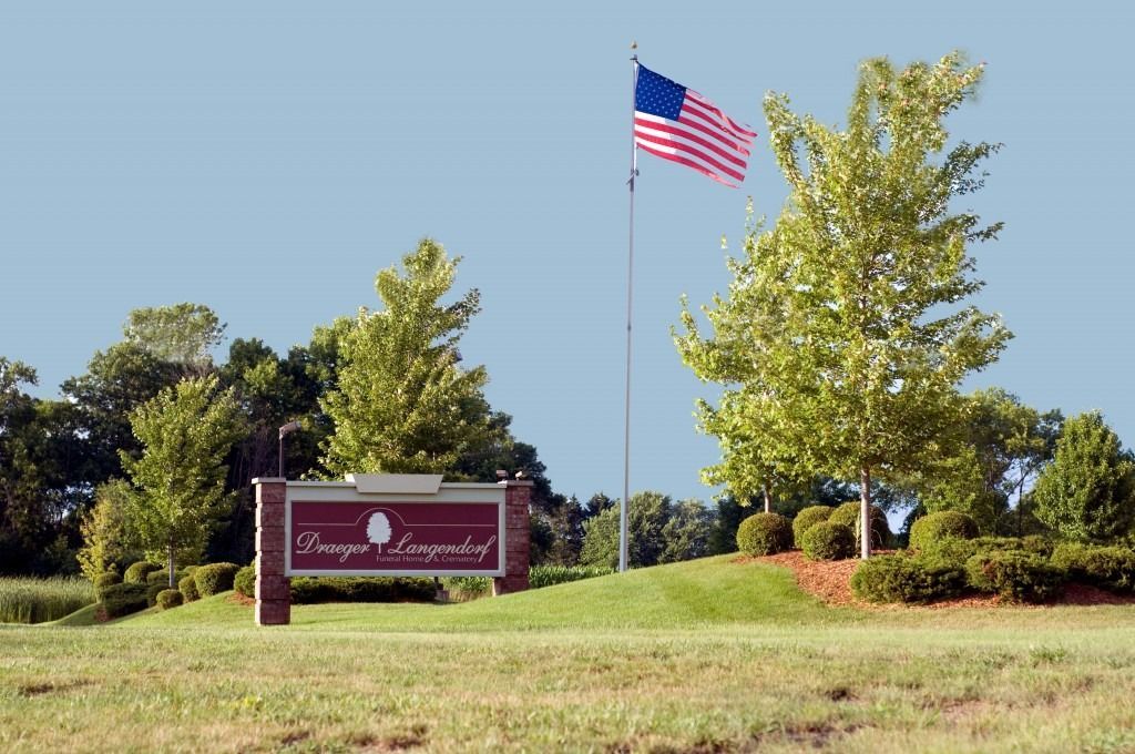 Red sign for Springfield, with an American flag on a pole in a landscaped roadside area.