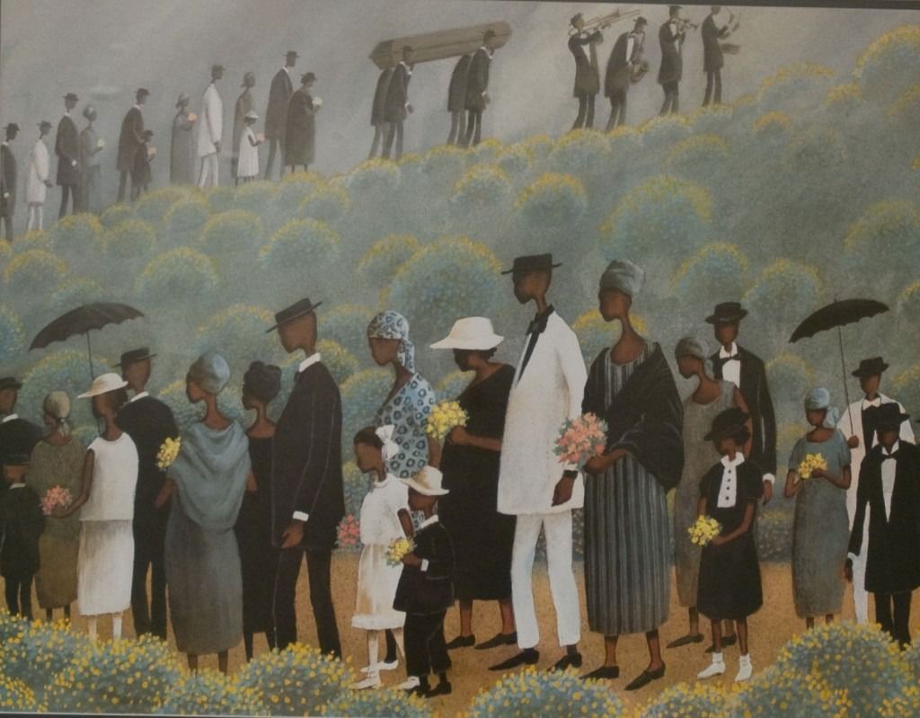 Crowd in formal attire gathers on a flowered hillside beneath a cloudy sky, many holding black umbrellas.