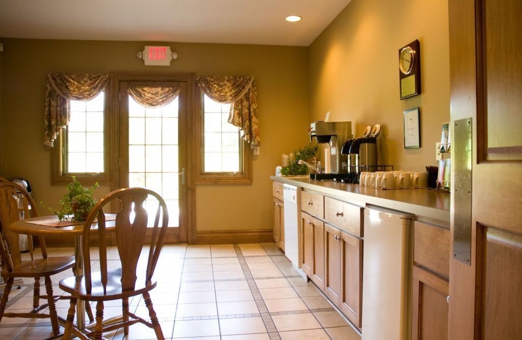 Empty dining room with wooden table and chairs, tiled floor, and a long buffet counter along the wall.
