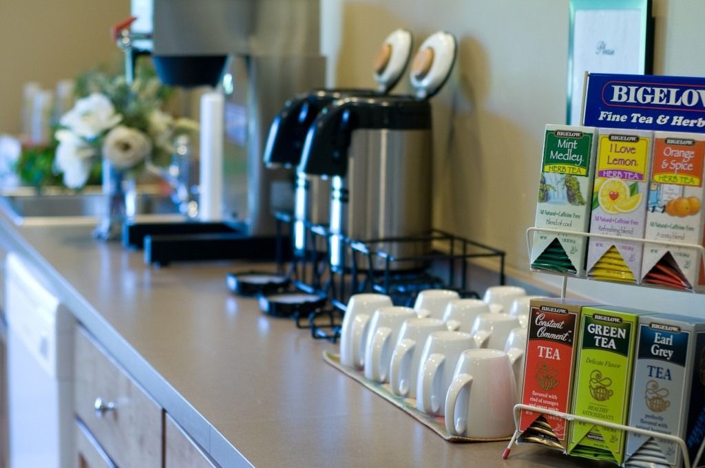 Tea and coffee station with mugs, kettles, and tea boxes on a countertop