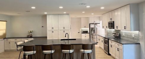 Bright modern kitchen with white cabinets, island seating, and stainless steel appliances