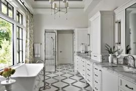 Bright white bathroom with clawfoot tub, patterned tile floor, and large windows overlooking greenery
