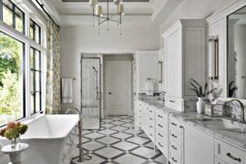 Bright white bathroom with clawfoot tub, patterned tile floor, and large windows overlooking greenery