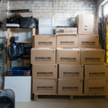 Stacked Shurgard self-storage boxes in a garage or storage room with shelves and bins.