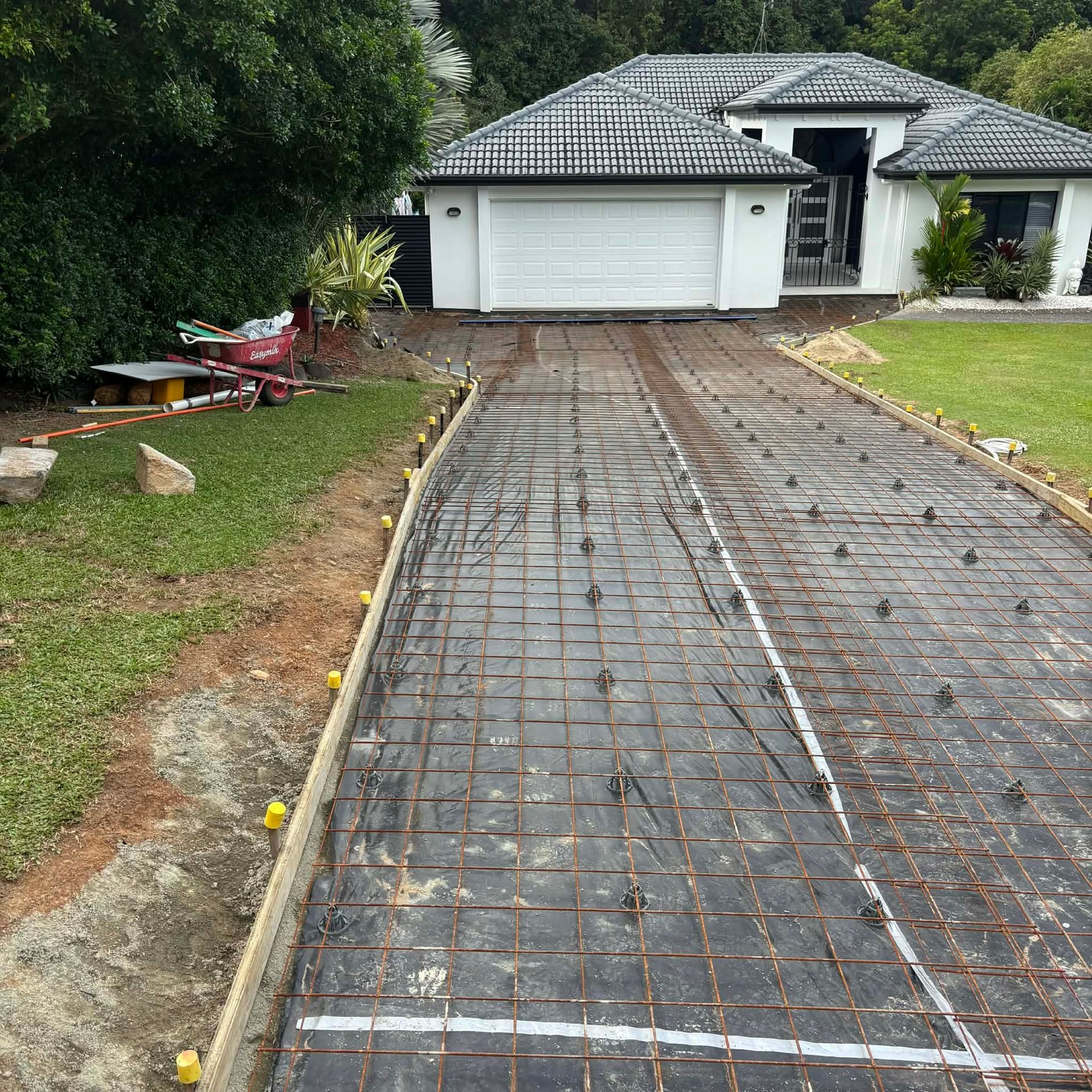 A gloved hand uses a metal trowel to smooth a layer of wet gray concrete.