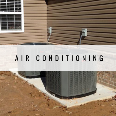 Two air conditioning units installed on a concrete slab against a building.