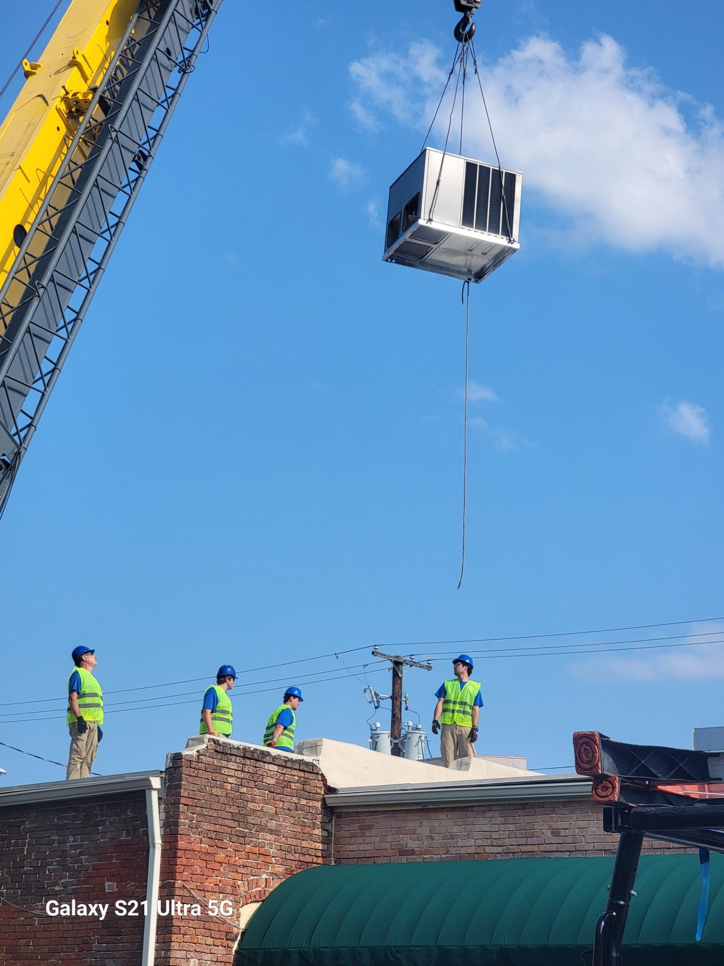 Two dark gray HVAC units on a concrete pad next to a light gray house.