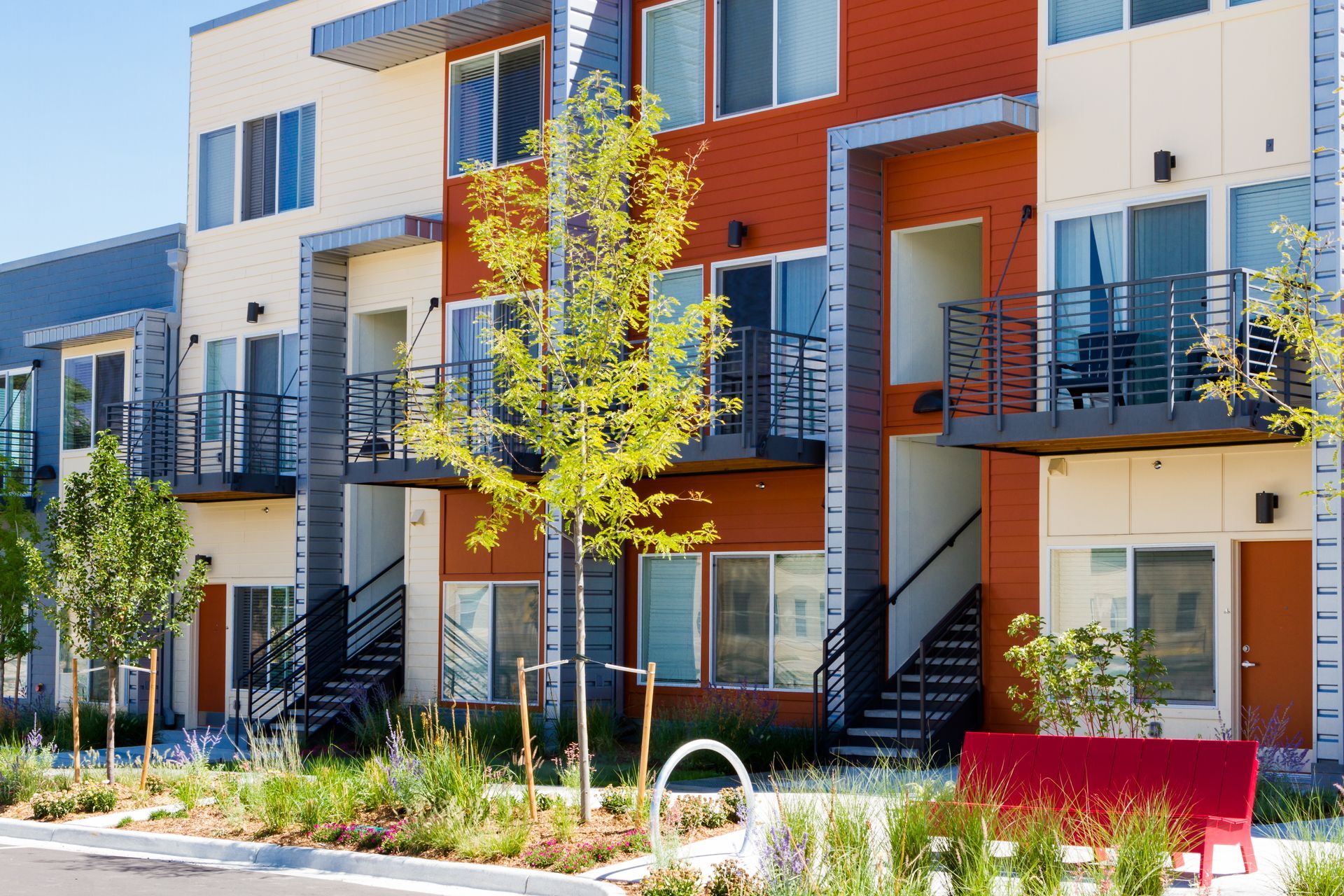 Modern apartment buildings with orange balconies and landscaped courtyard trees