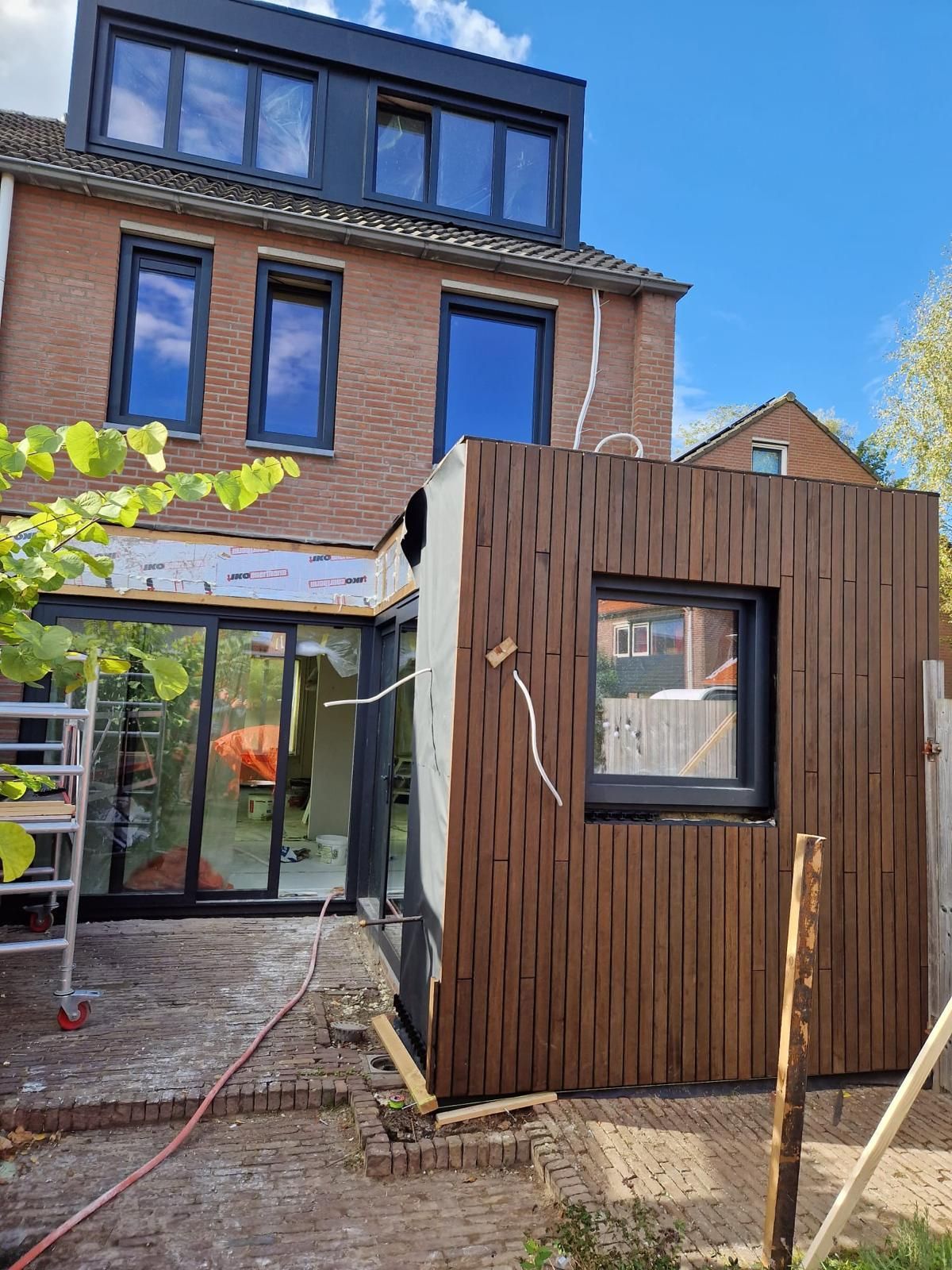Een bakstenen huis met een houten uitbouw aan de zijkant.