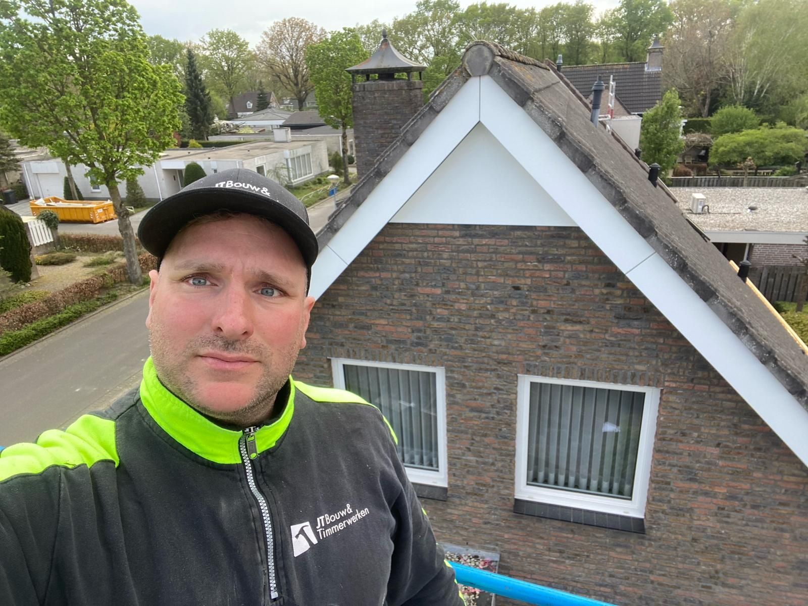 Een man neemt een selfie voor een bakstenen huis.